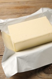 Block of tasty butter on wooden table, closeup