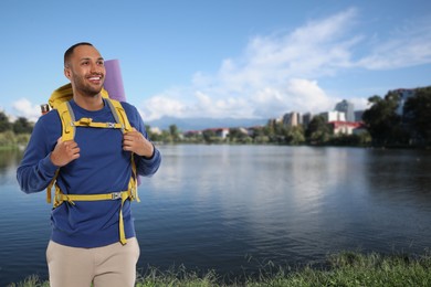 Image of Happy tourist with yellow backpack near lake