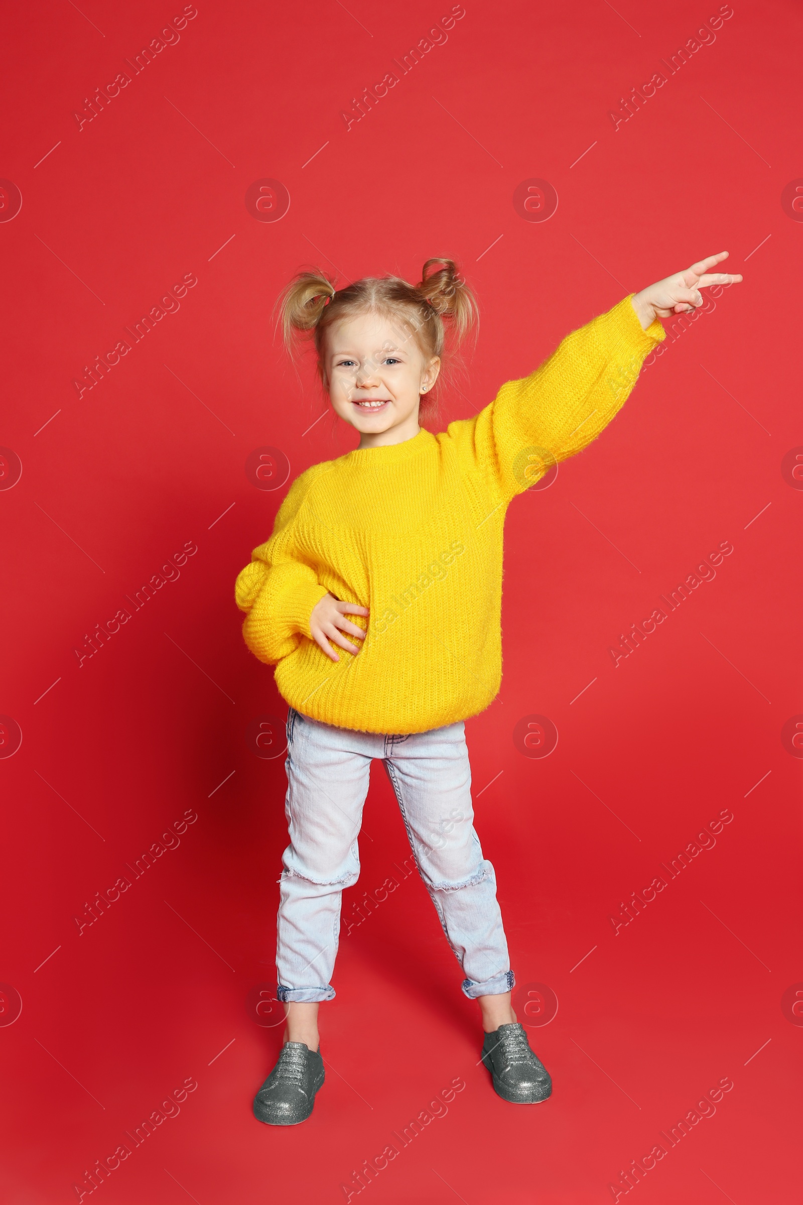 Photo of Cute little girl dancing on red background