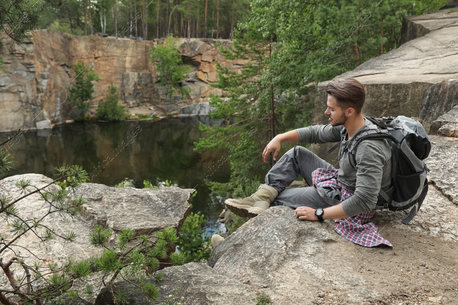 Photo of Young man on rocky mountain near lake. Camping season