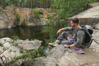 Young man on rocky mountain near lake. Camping season