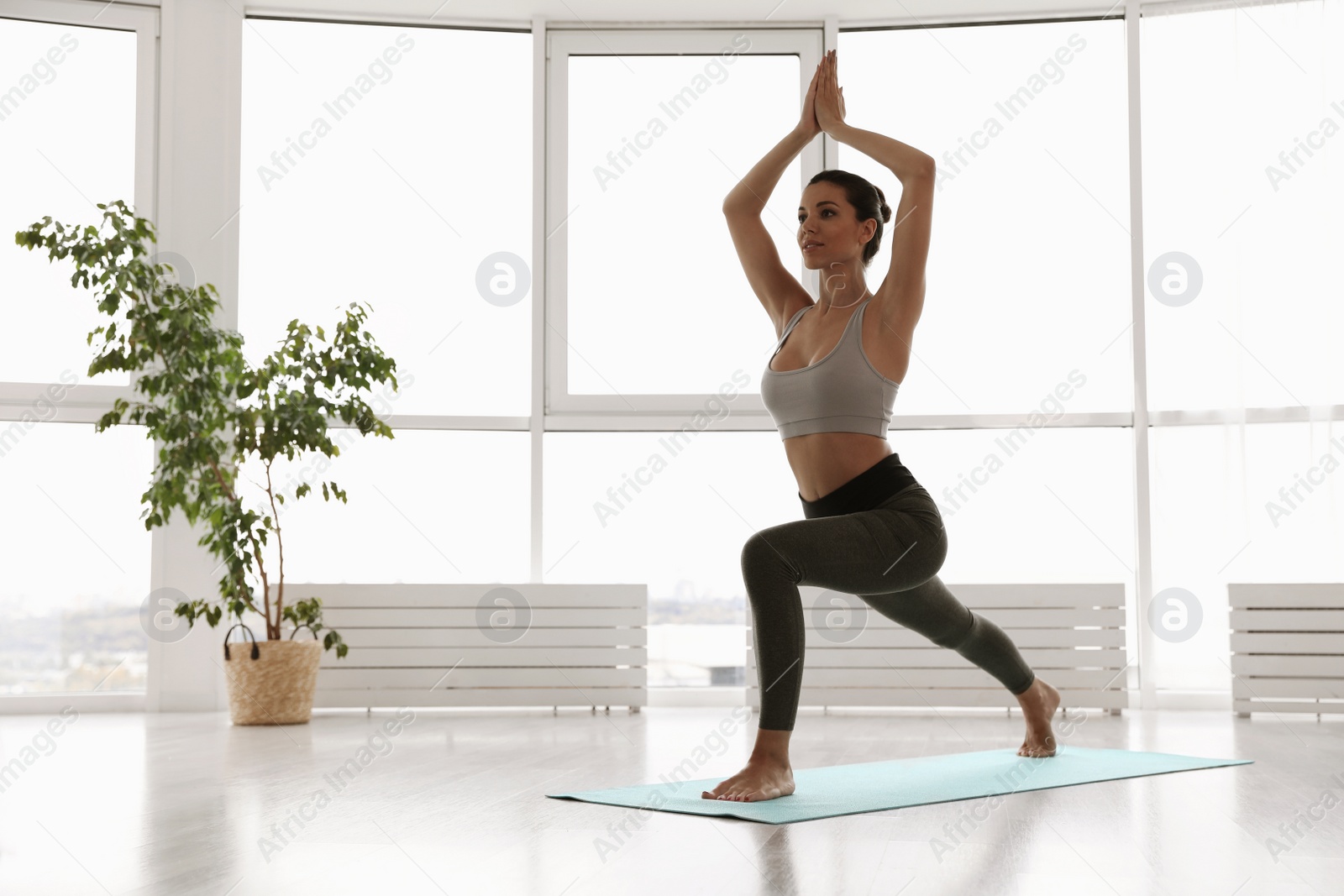 Photo of Young woman practicing crescent asana in yoga studio. High lunge pose