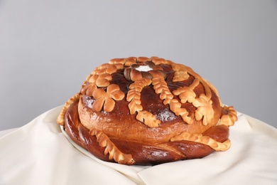 Photo of Korovai on tablecloth against grey background. Ukrainian bread and salt welcoming tradition