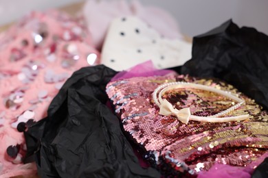 Photo of Headbands and stylish pink carnival costume with sequins in black box, closeup