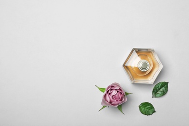 Photo of Bottle of perfume and rose on light background, top view