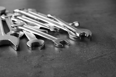 Photo of New wrenches on grey background, closeup with space for text. Plumber tools