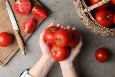 Woman with ripe tomatoes at grey table, top view