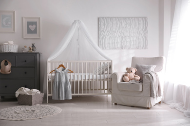 Photo of Baby room interior with comfortable crib and armchair