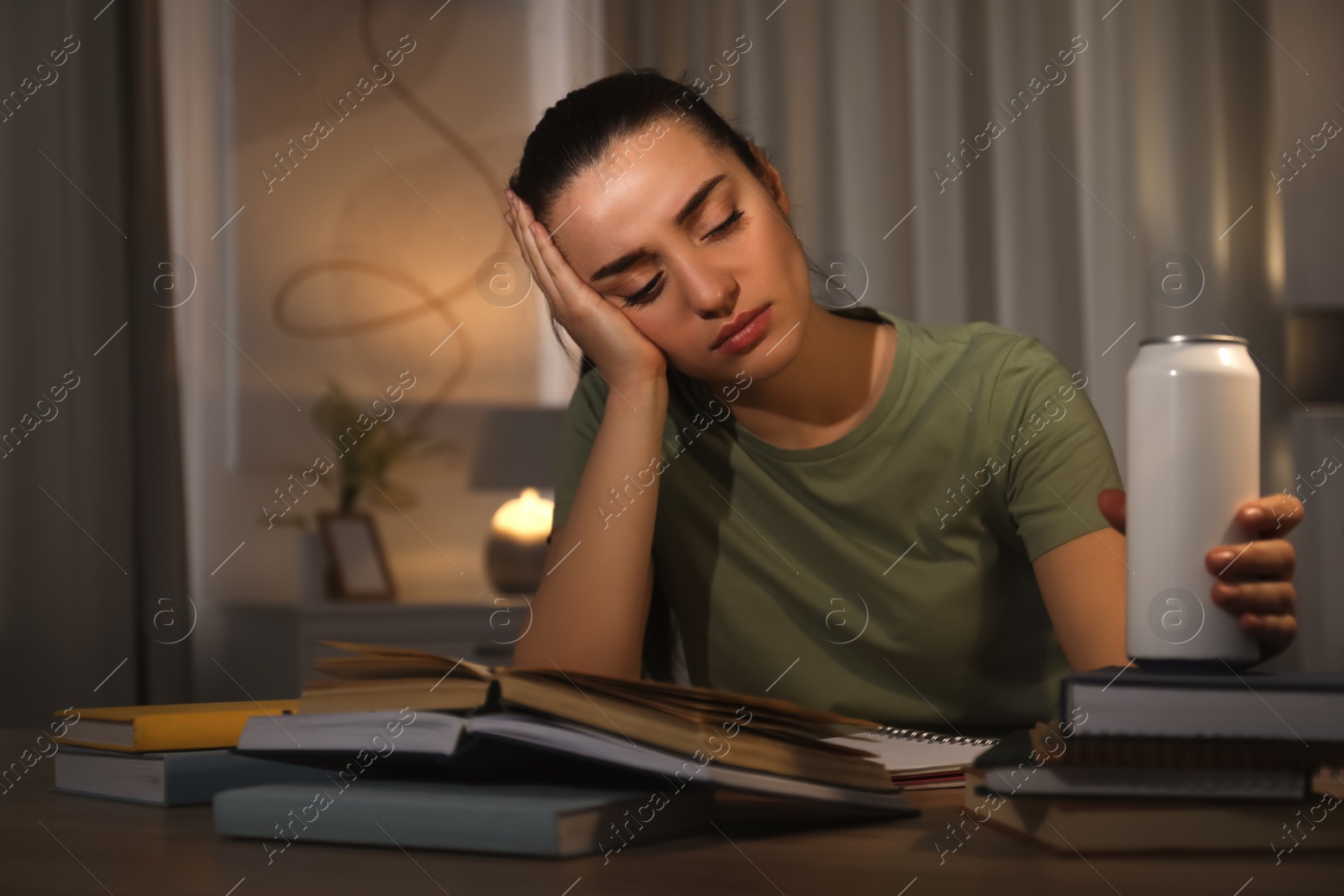 Photo of Tired young woman with energy drink studying at home