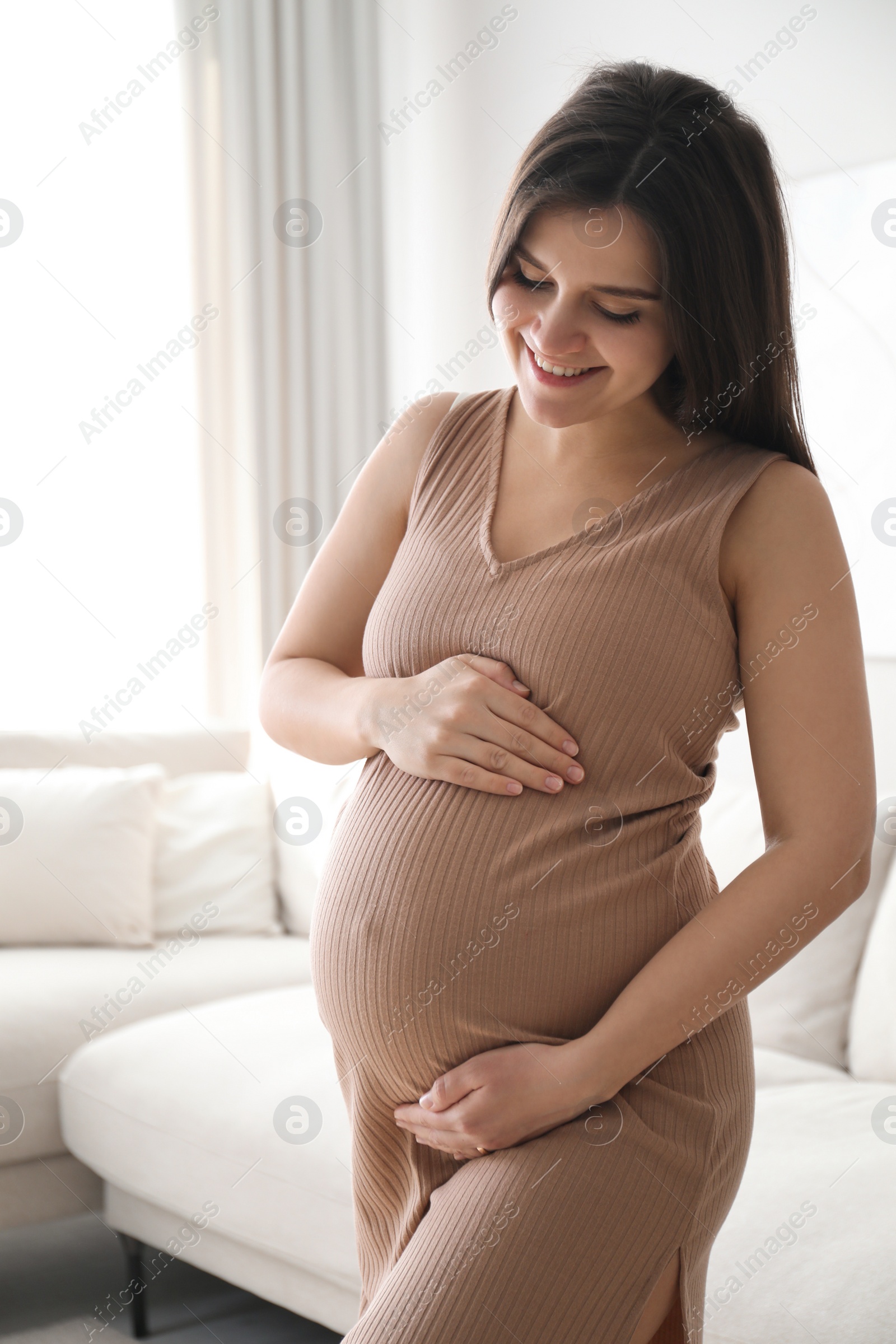 Photo of Pregnant young woman touching belly at home