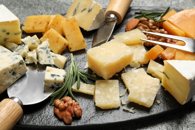 Photo of Cheese platter with specialized knives and fork on table, closeup view