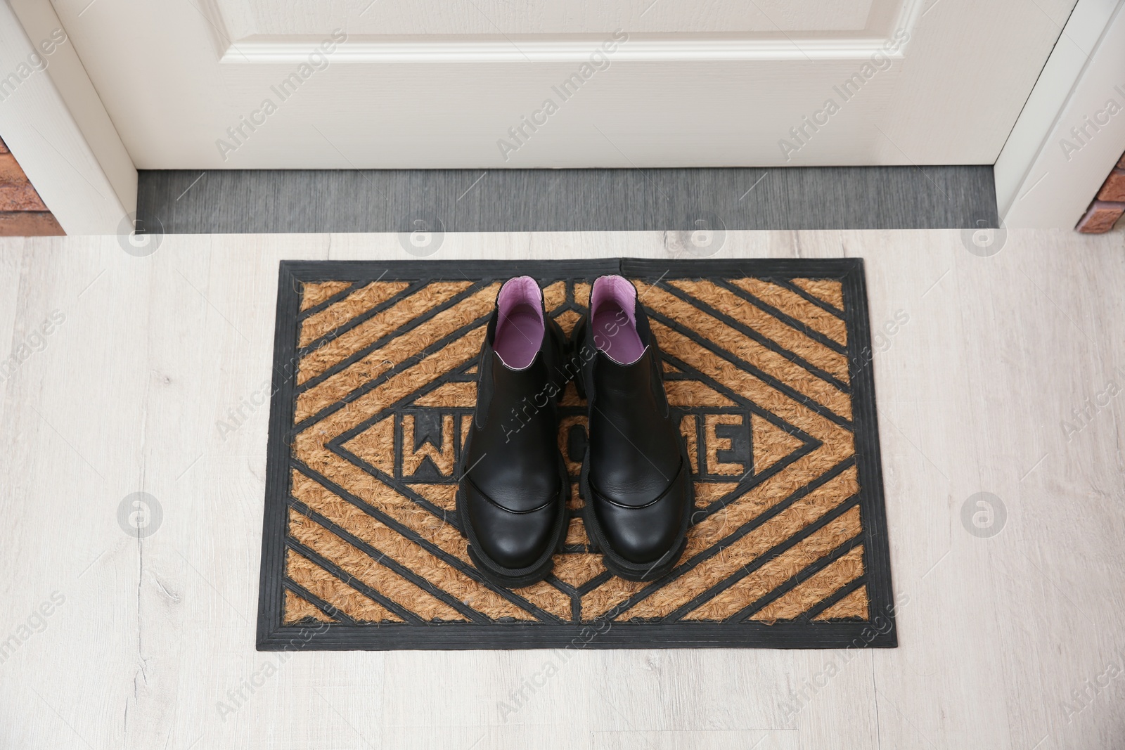 Photo of Stylish shoes on door mat in hall, above view