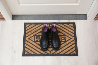 Photo of Stylish shoes on door mat in hall, above view