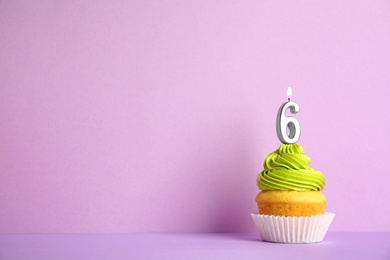 Birthday cupcake with number six candle on violet background, space for text