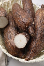 Photo of Whole and cut cassava roots on table, closeup