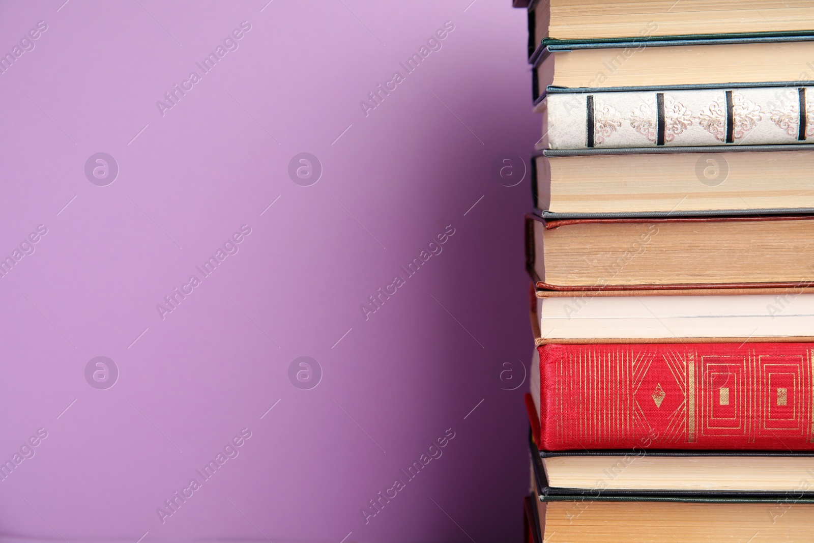 Photo of Stack of hardcover books on violet background. Space for text