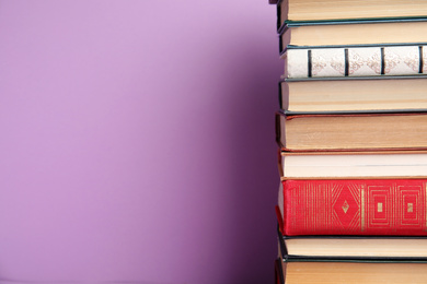 Photo of Stack of hardcover books on violet background. Space for text