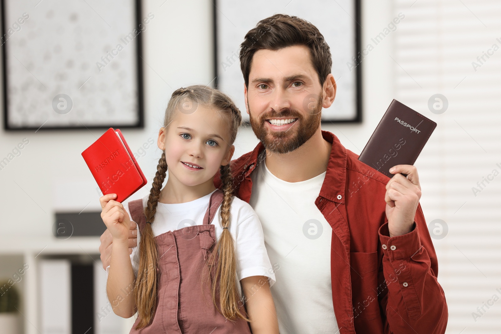 Photo of Immigration. Happy man and his daughter with passports indoors