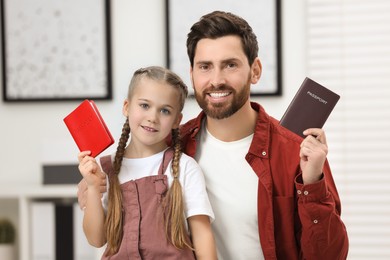 Immigration. Happy man and his daughter with passports indoors