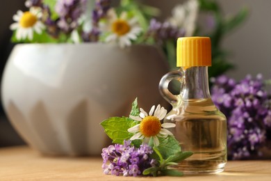 Bottle of natural lavender essential oil near mortar with flowers on wooden table, closeup. Space for text