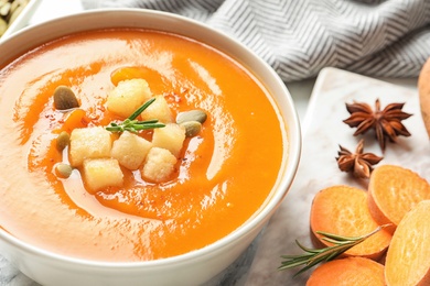 Photo of Bowl of tasty sweet potato soup on served table, closeup. Space for text