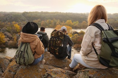 Photo of Group of friends with backpacks near mountain river, back view