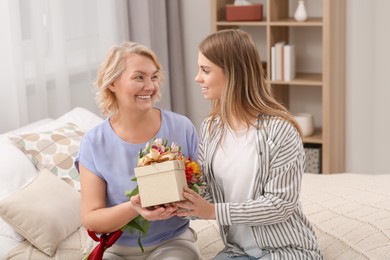 Young daughter congratulating her mom with gift at home. Happy Mother's Day