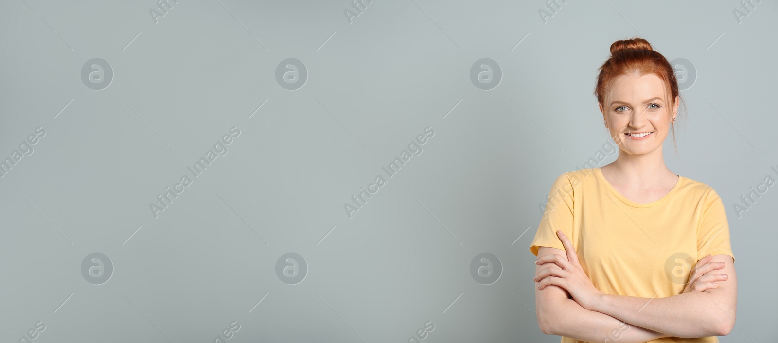 Photo of Candid portrait of happy red haired woman with charming smile on light grey background, space for text