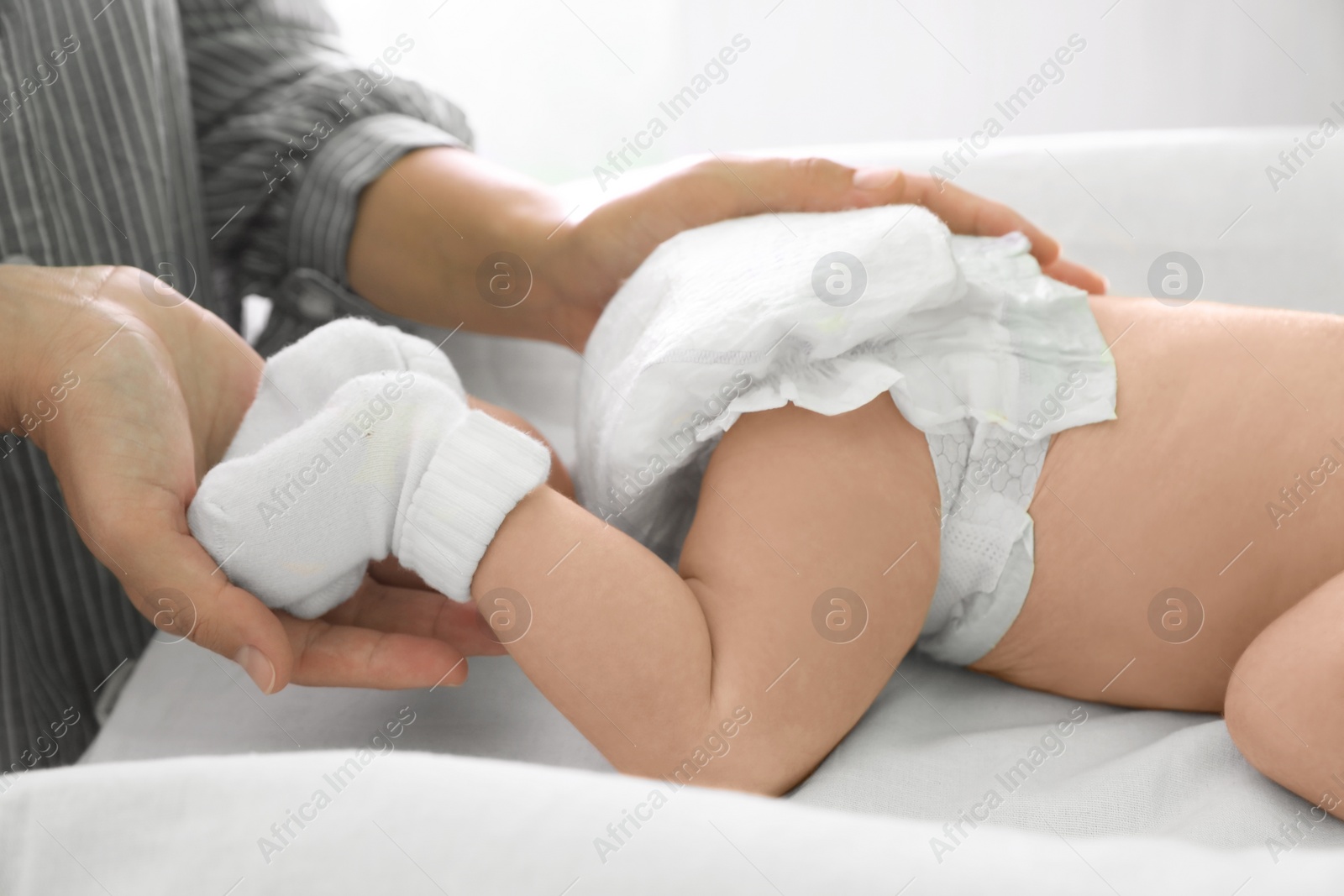 Photo of Mother massaging her little baby on changing table indoors, closeup