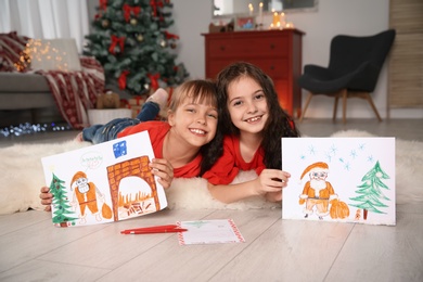 Photo of Little children with drawings and letter to Santa at home. Christmas celebration