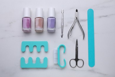 Photo of Set of pedicure tools on white marble table, flat lay