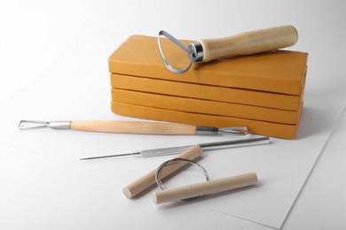 Photo of Clay and different modeling tools on white background