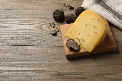 Photo of Delicious cheese and fresh black truffles on wooden table, above view. Space for text
