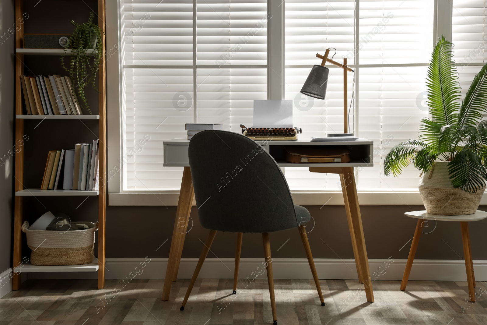 Photo of Comfortable writer's workplace interior with typewriter on desk in front of window