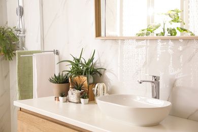 Stylish bathroom interior with countertop, mirror and houseplants. Design idea