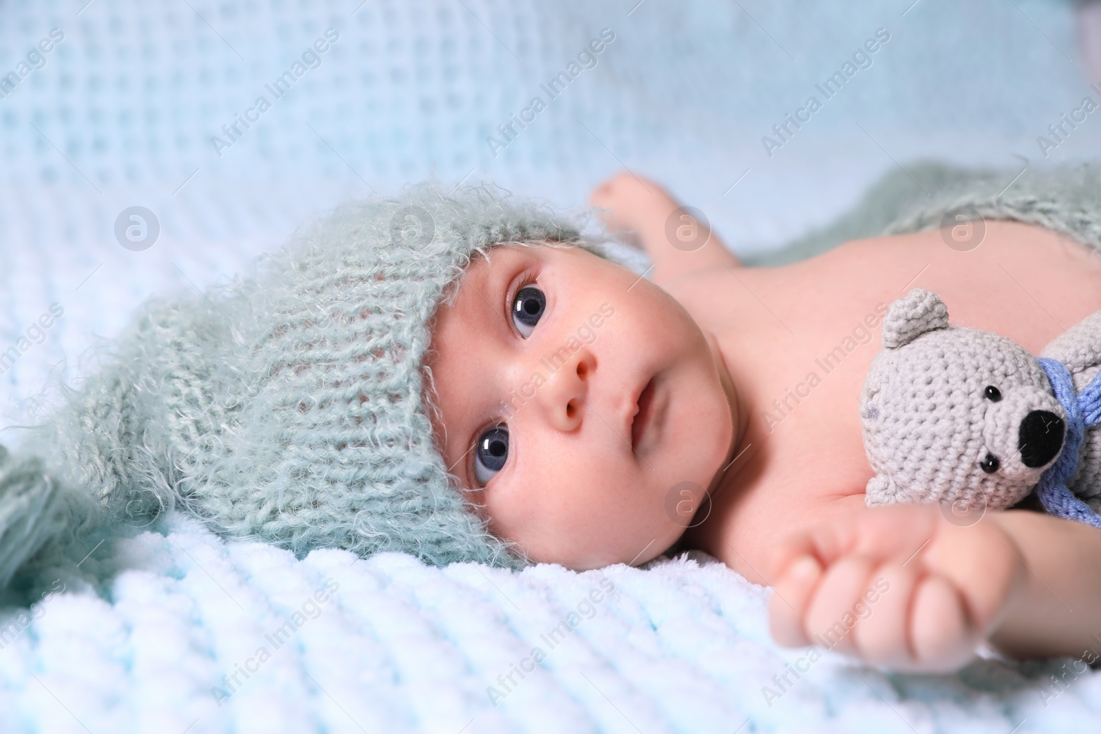 Photo of Cute newborn baby with crochet toy on light blue blanket