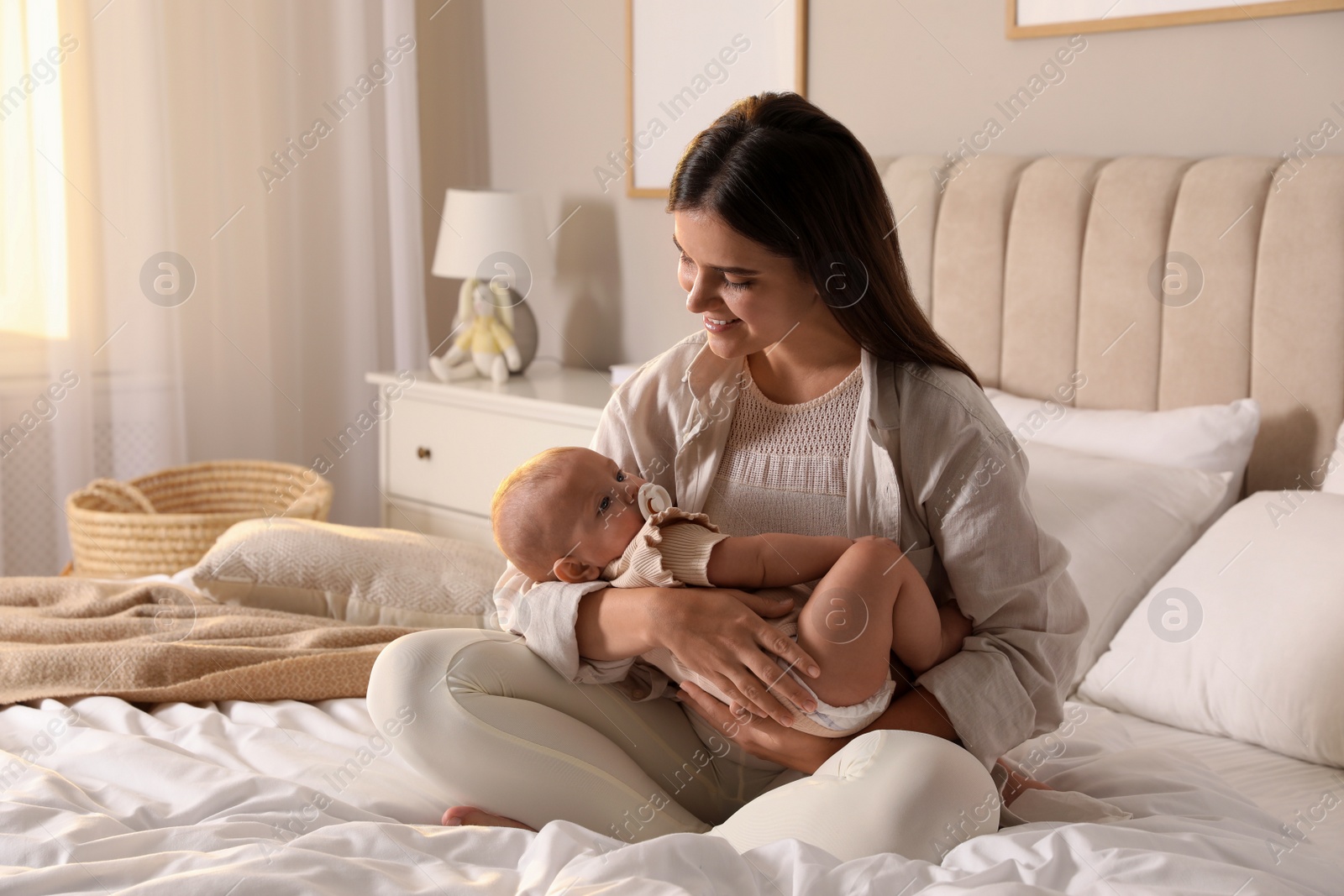 Photo of Young woman with her little baby on bed at home