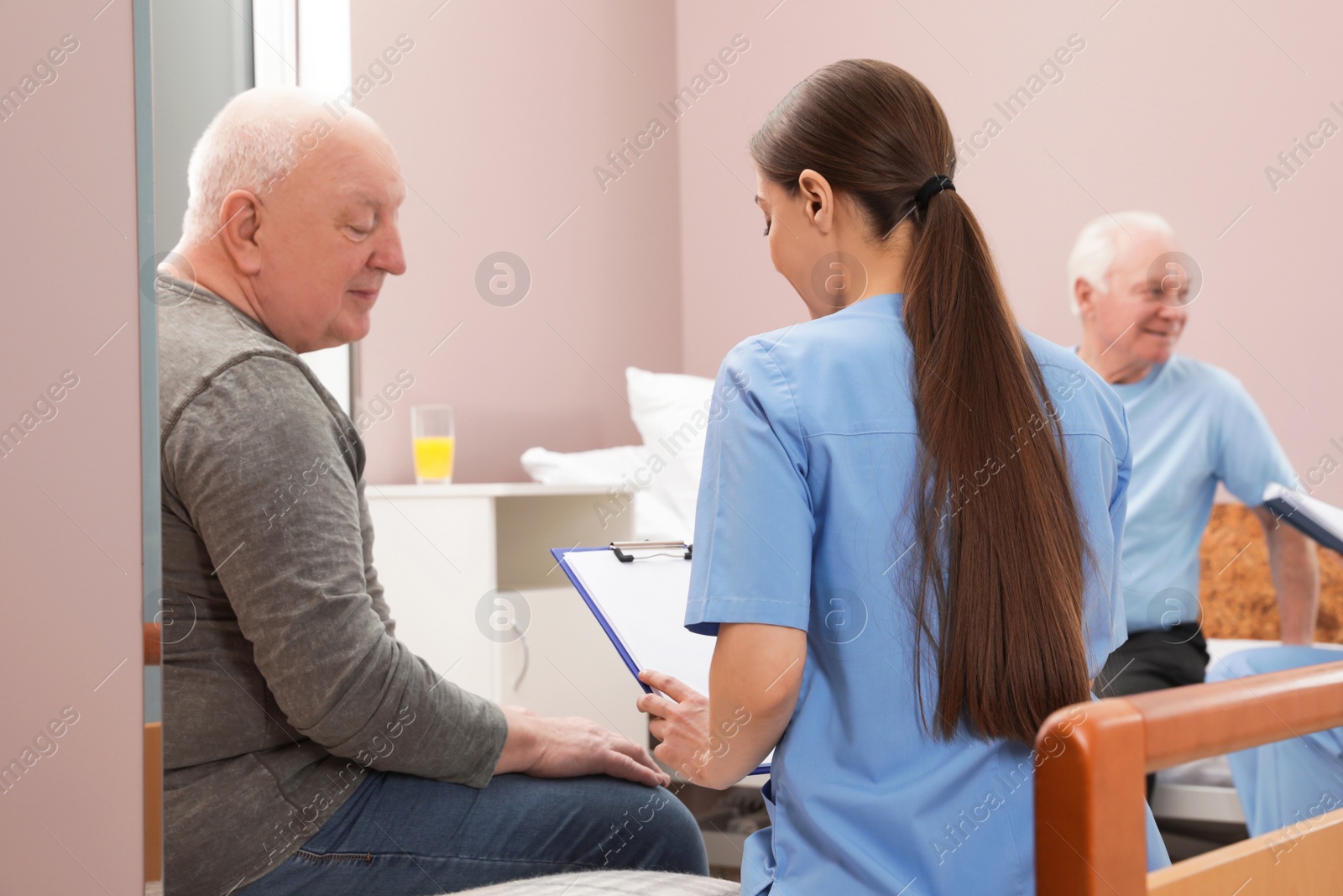 Photo of Nurse talking with senior patient in hospital ward. Medical assisting