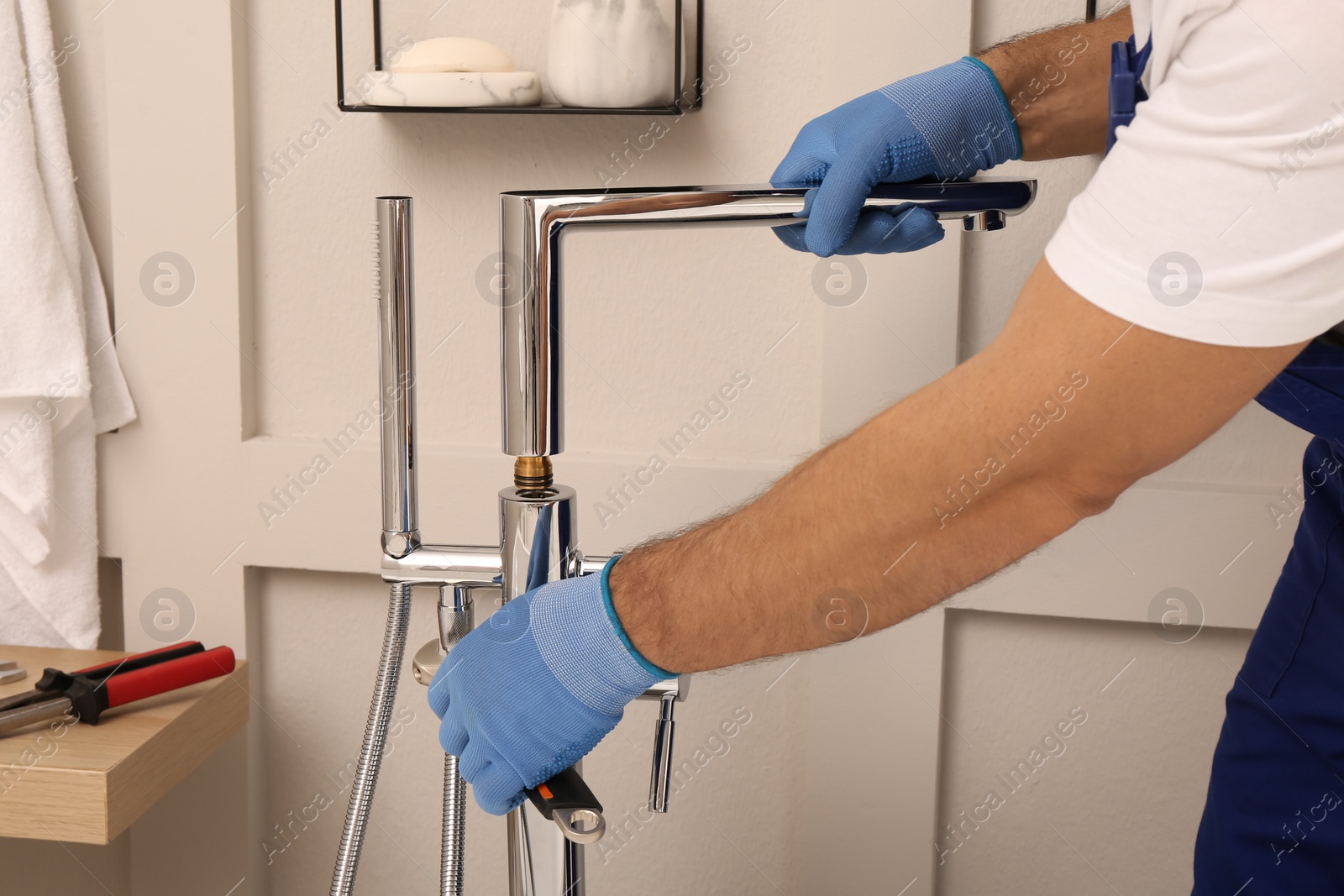 Photo of Professional plumber installing water tap in bathroom, closeup
