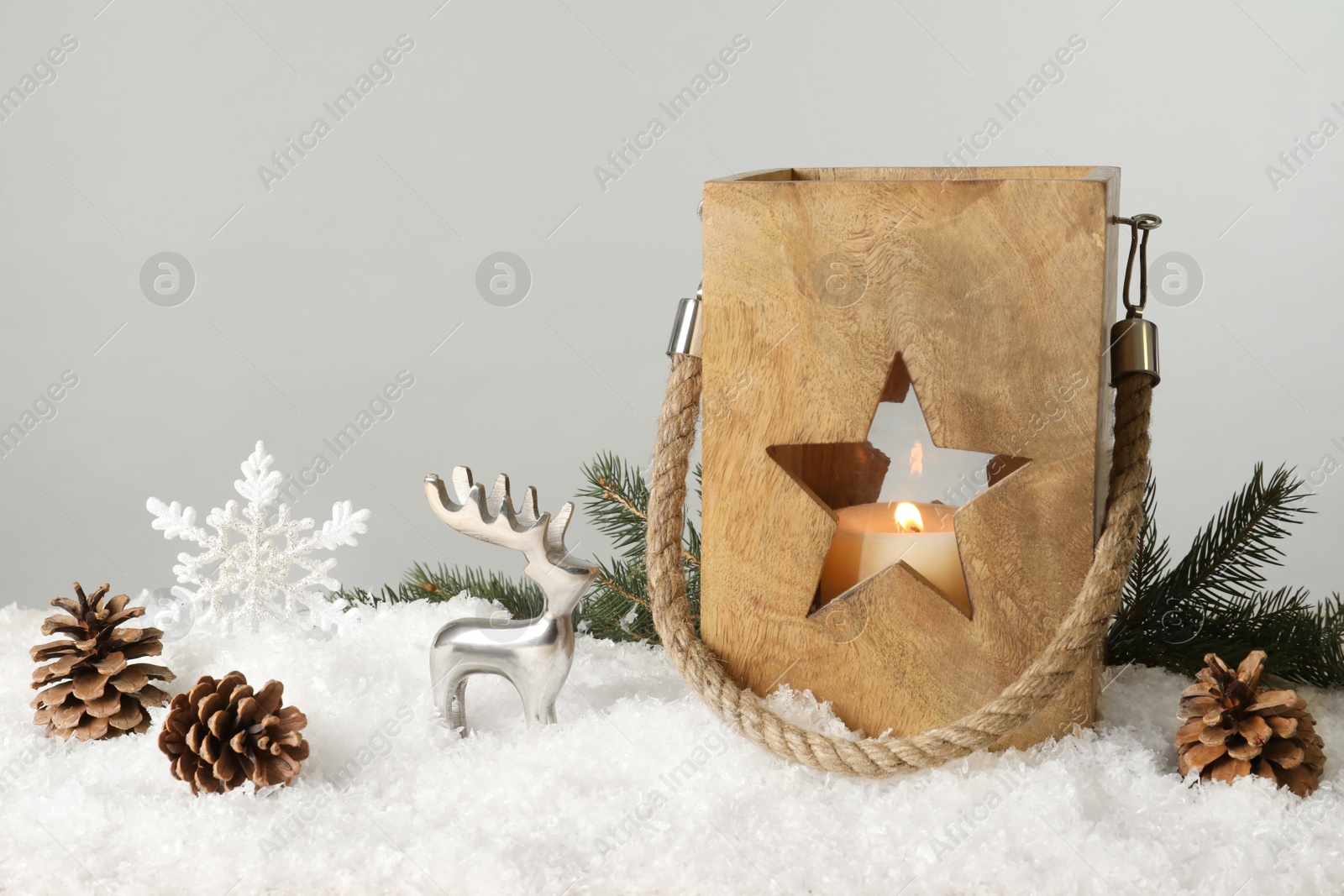 Photo of Composition with wooden Christmas lantern on snow against light grey background, space for text