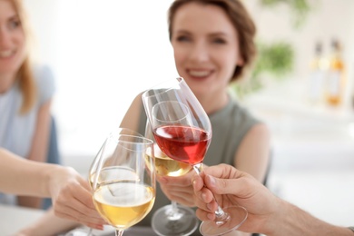 Young people with glasses of delicious wine indoors