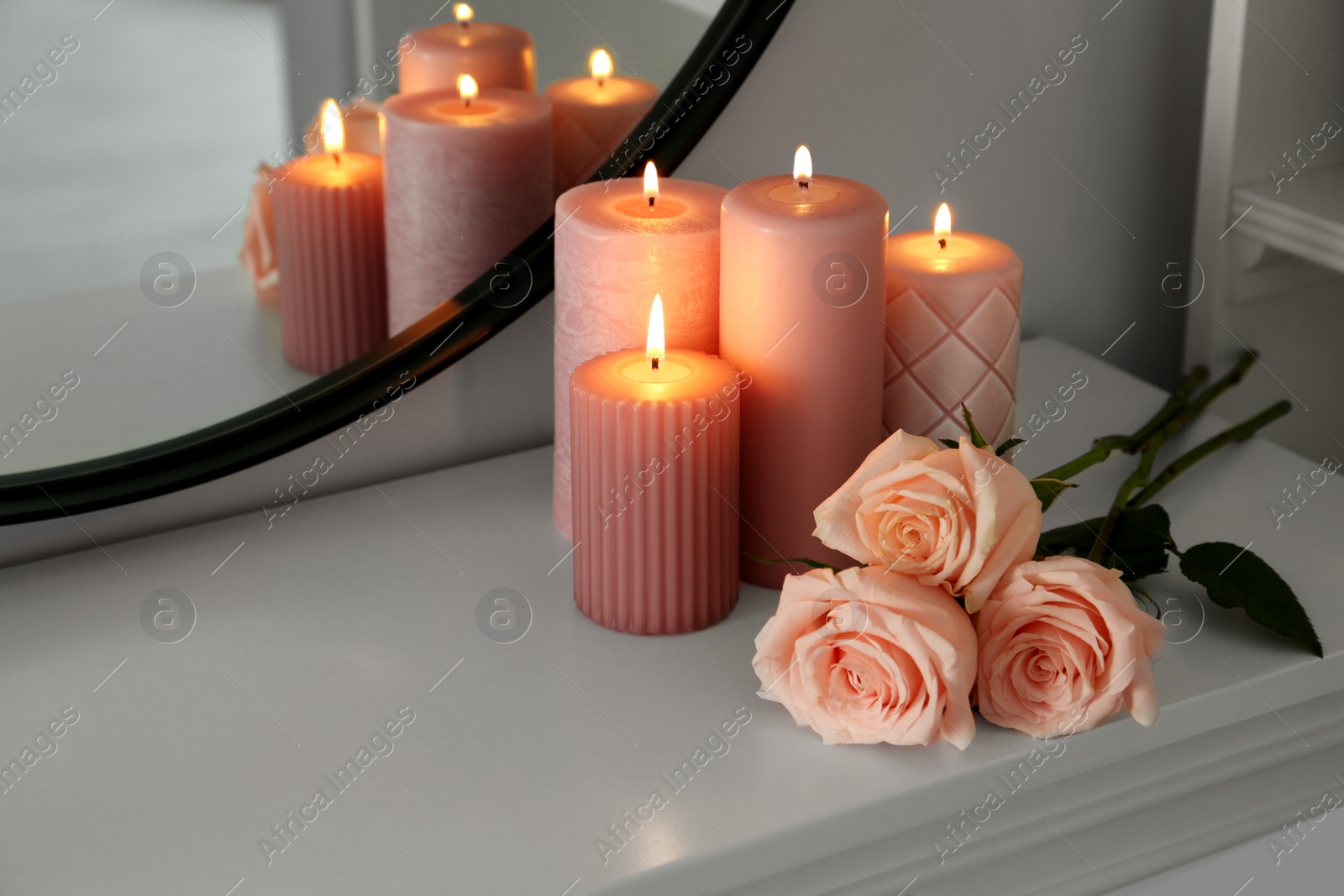 Photo of Burning candles and roses on white console table near mirror, space for text