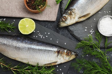 Photo of Delicious salted herrings and ingredients on dark grey table, flat lay
