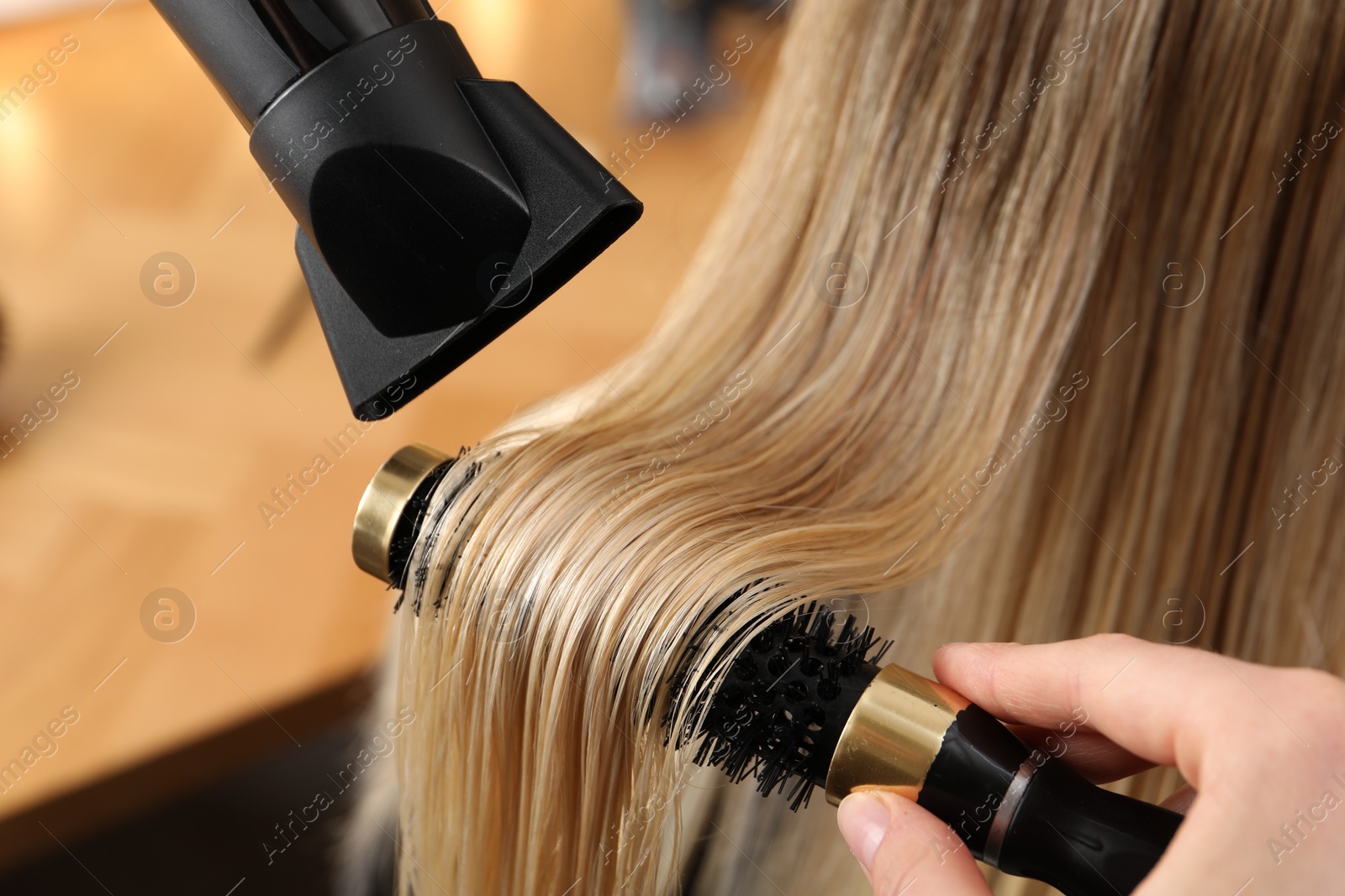 Photo of Hairdresser blow drying client's hair in salon, closeup