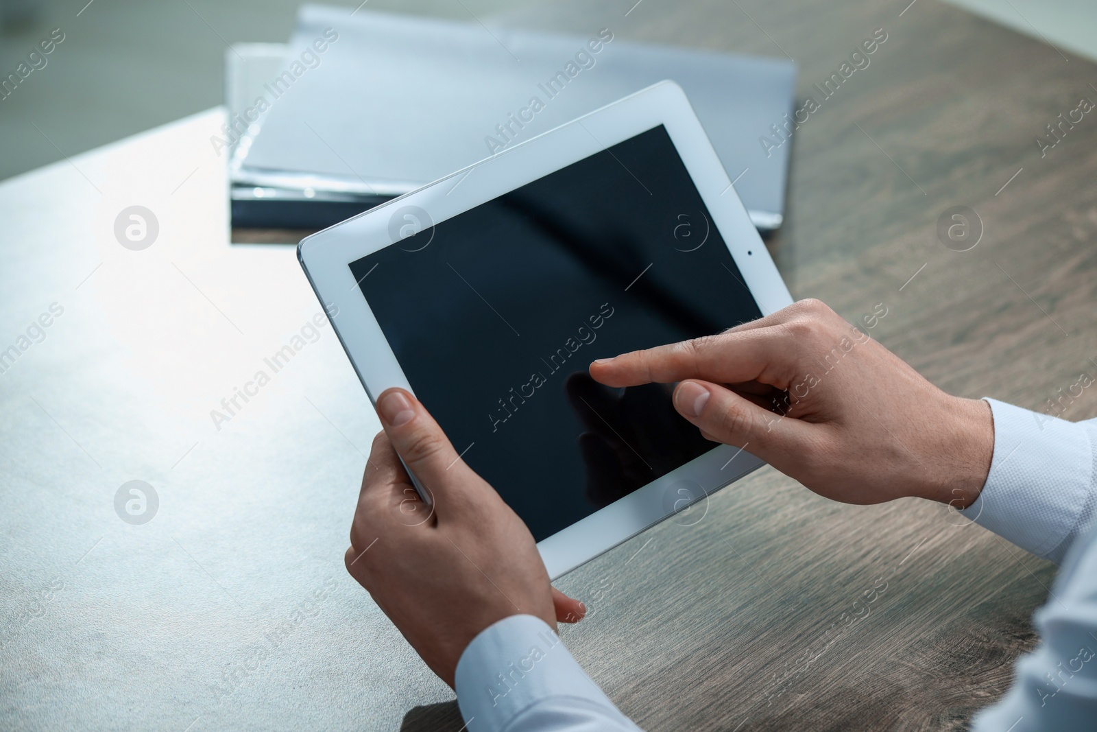 Photo of Man using tablet at wooden table, closeup