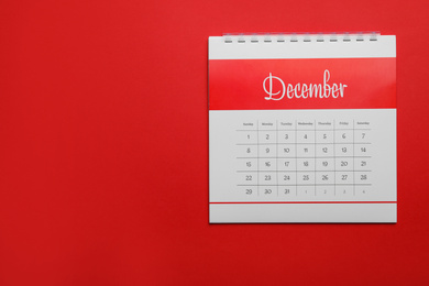 Photo of December calendar on red background, top view. Space for text