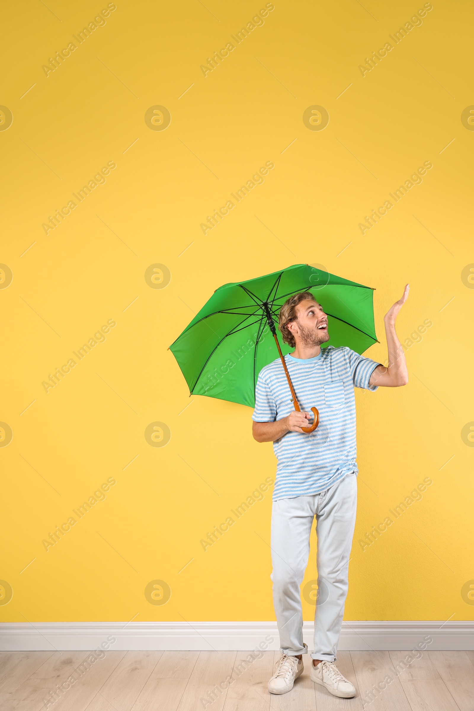 Photo of Man with green umbrella near color wall