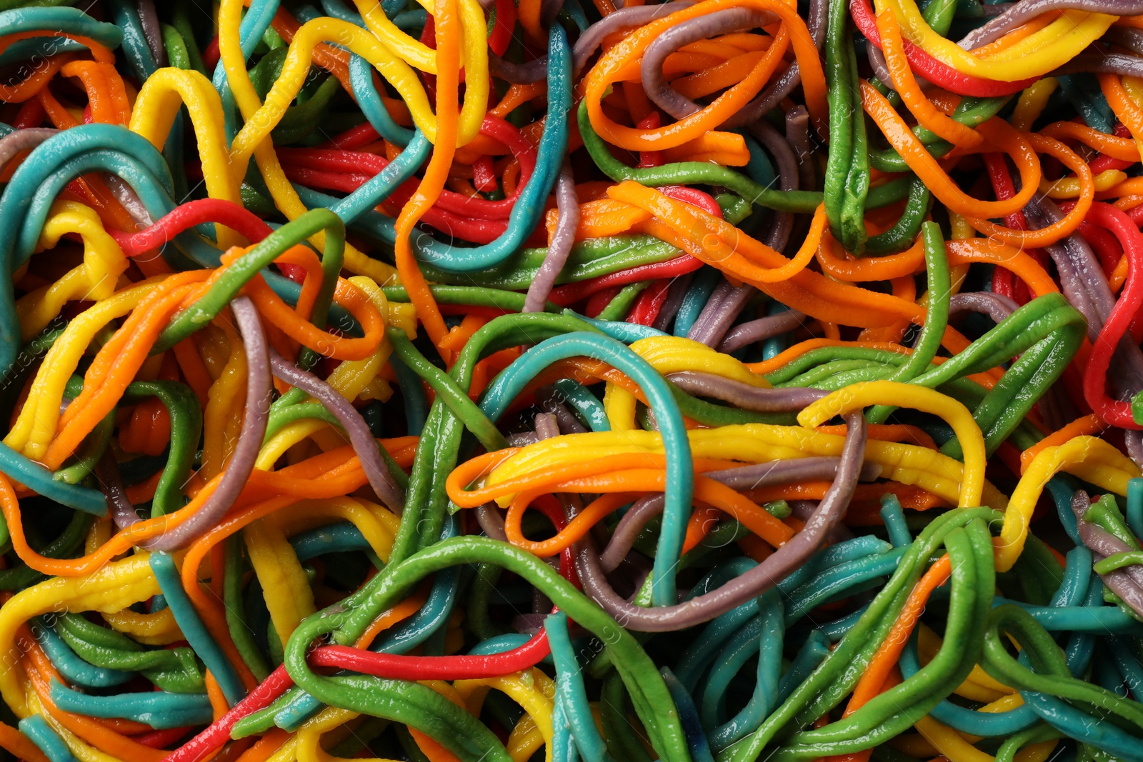 Photo of Spaghetti painted with different food colorings as background, closeup