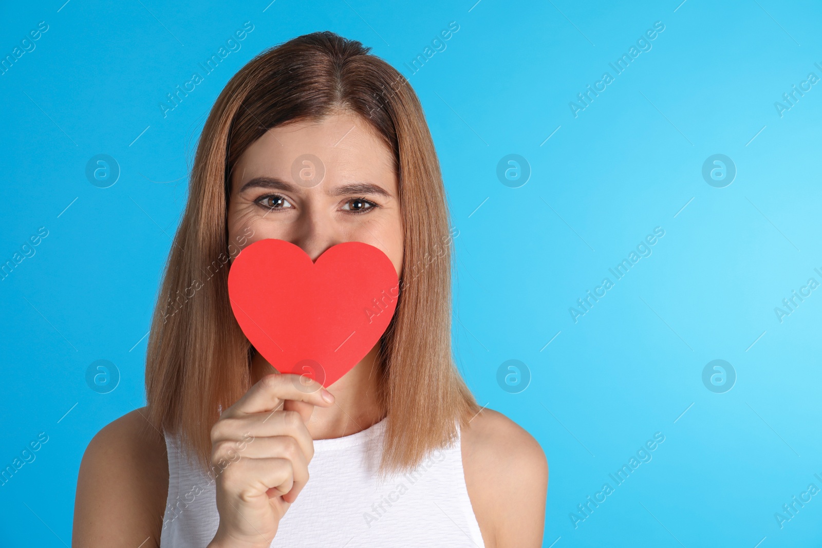 Photo of Portrait of woman with paper heart on color background. Space for text