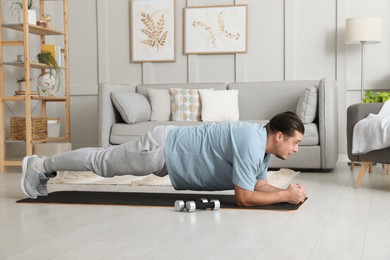 Photo of Overweight man doing plank exercise on mat at home